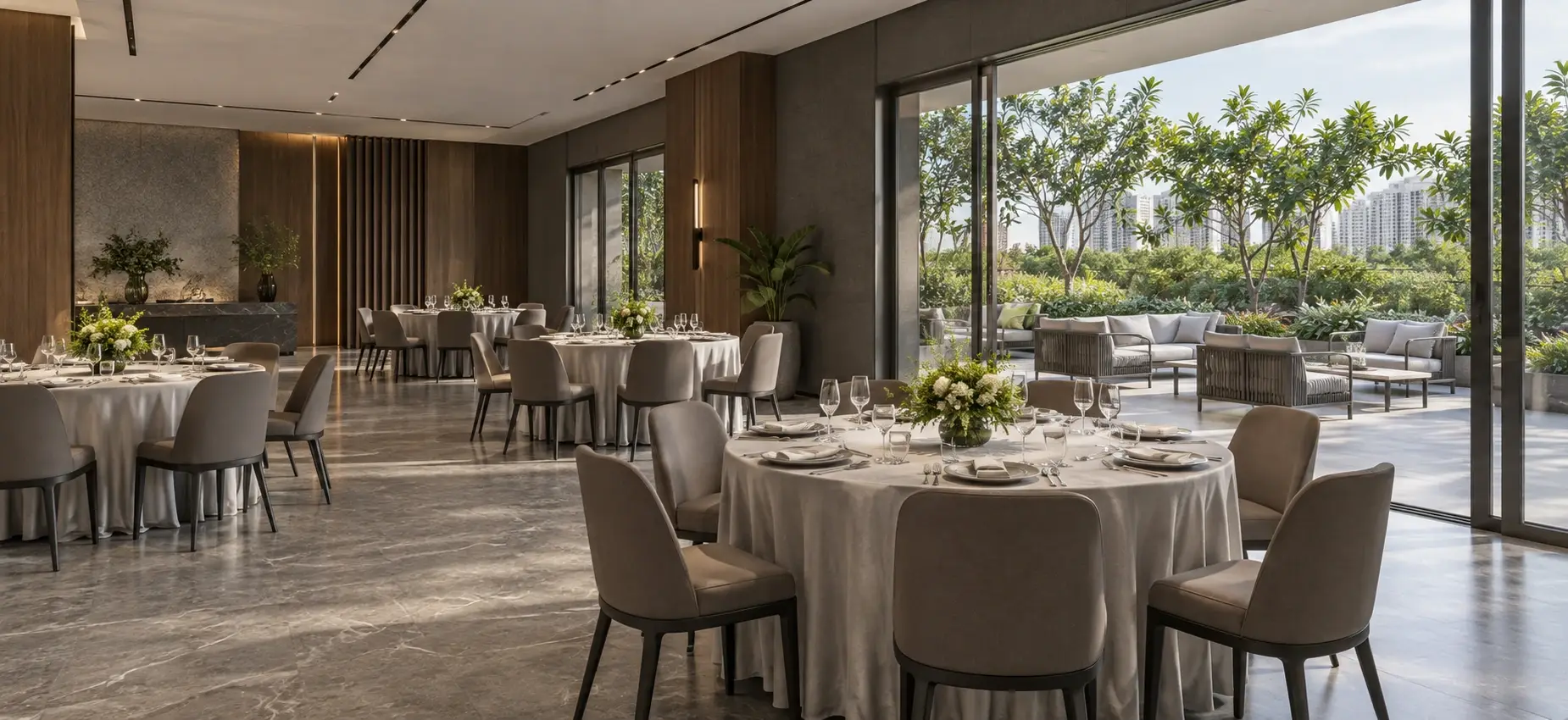 A banquet hall laid for dinner, floor-to-ceiling glass opening onto a garden terrace.